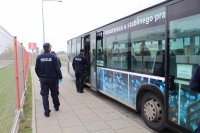 Zaparkowany autobus do którego wsiadają policjanci w celu sprawdzenia czy pasażerowie zakrywają nos i usta