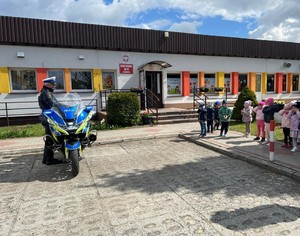 policjanci z przedszkolakami przy radiowozie i motocyklu policyjnym