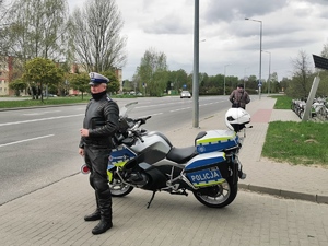 policjant ruchu drogowego stoi przy motocyklu słuzbowym