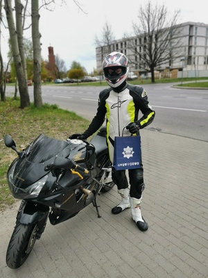 motocyklista z otrzymanym upominkiem stoi obok swojego motocykla