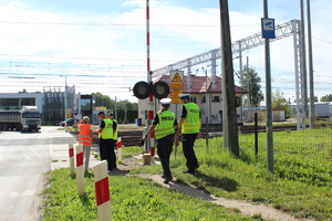 Policjanci, pracownicy kolei oraz straż ochrony kolei stoją przy przejeździe