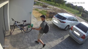 mężczyzna w krótkich spodenkach, butach sportowych podchodzi do roweru opartego o budynek mieszkalny