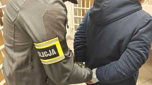 Policjanci zakładają kajdanki na ręce.