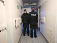 Policjant prowadzi zatrzymanego mężczyznę do celi.