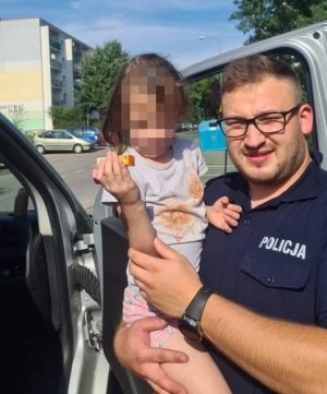 Policjant trzyma na rękach znalezioną dziewczynkę.