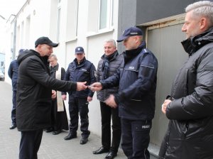 Starosta przekazuje kluczyki auta mundurowemu. Dookoła pozostali goście.