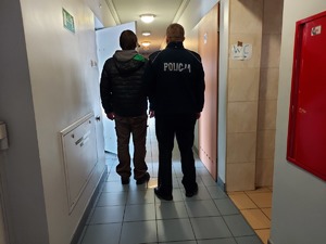 Policjant prowadzi zatrzymanego do celi.