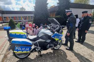 policjanci z przedszkolakami przy radiowozie i motocyklu policyjnym