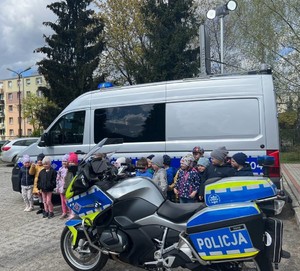 policjanci z przedszkolakami przy radiowozie i motocyklu policyjnym