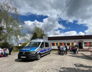 policjanci z przedszkolakami przy radiowozie i motocyklu policyjnym