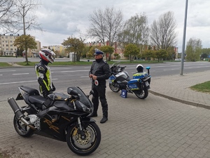 policjant ruchu drogowego rozmawia z zatrzymanym do kontroli motocyklistą