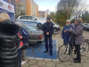 policjant rozmawia z seniorami na parkingu