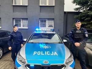 Umundurowani policjanci stoją przy radiowozie.