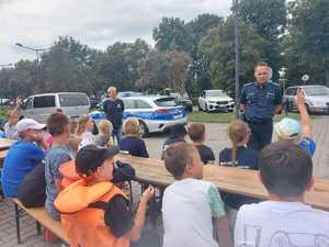 policjant zadaje pytania na temat bezpieczeństwa dzieciom podczas spotkania profilaktycznego.