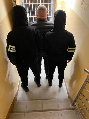 policjanci osadzają zatrzymanego w policyjnej izbie zatrzymań.