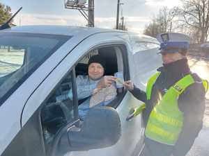 policjantka wręcza zawieszkę zapachową kierowcy podczas kampanii zwolnij jak kocha to poczeka.