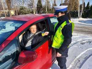 policjantka wręcza zawieszkę zapachową kierowcy podczas kampanii zwolnij jak kocha to poczeka.