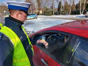 policjant wręcza zawieszkę zapachową kierowcy podczas kampanii zwolnij jak kocha to poczeka.