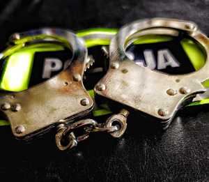 Kajdanki leżące na opasce z napisem Policja