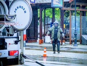 Funkcjonariusz w kombinezonie niosący zabezpieczoną walizkę