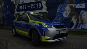 Radiowóz policyjny na tle muralu z gwiazda policyjną.