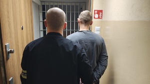 Policjant z prowadzi zatrzymanego mężczyznę