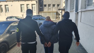 Policjanci prowadza zatrzymanego do radiowozu