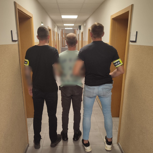 Policjanci trzymają zatrzymanego.