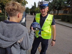 Policjant wręcza kask dziecku