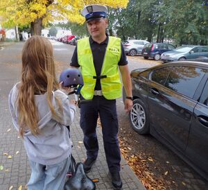 Policjant wręcza kask dziecku